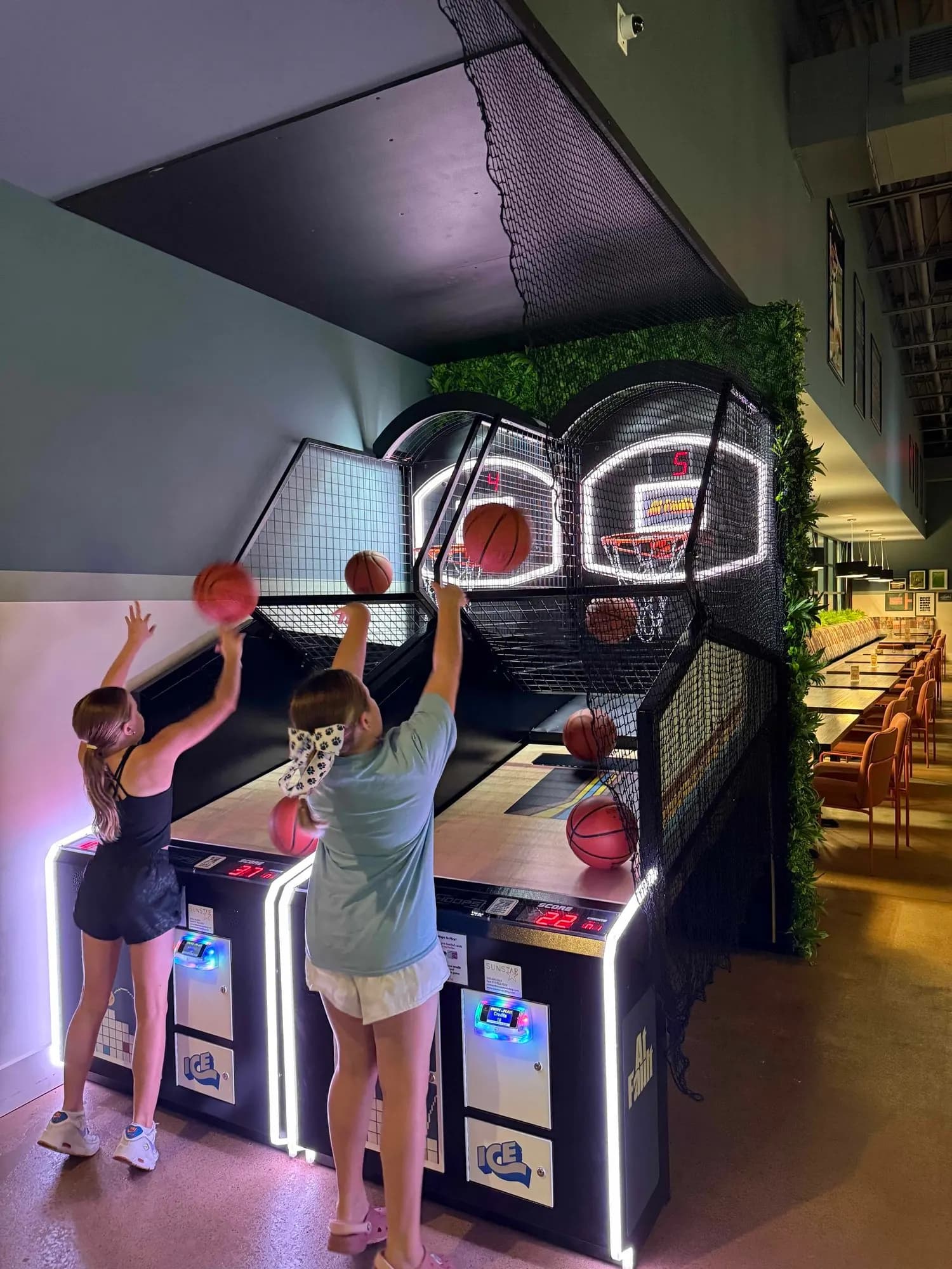 Adults playing basketball arcade games at At Fault